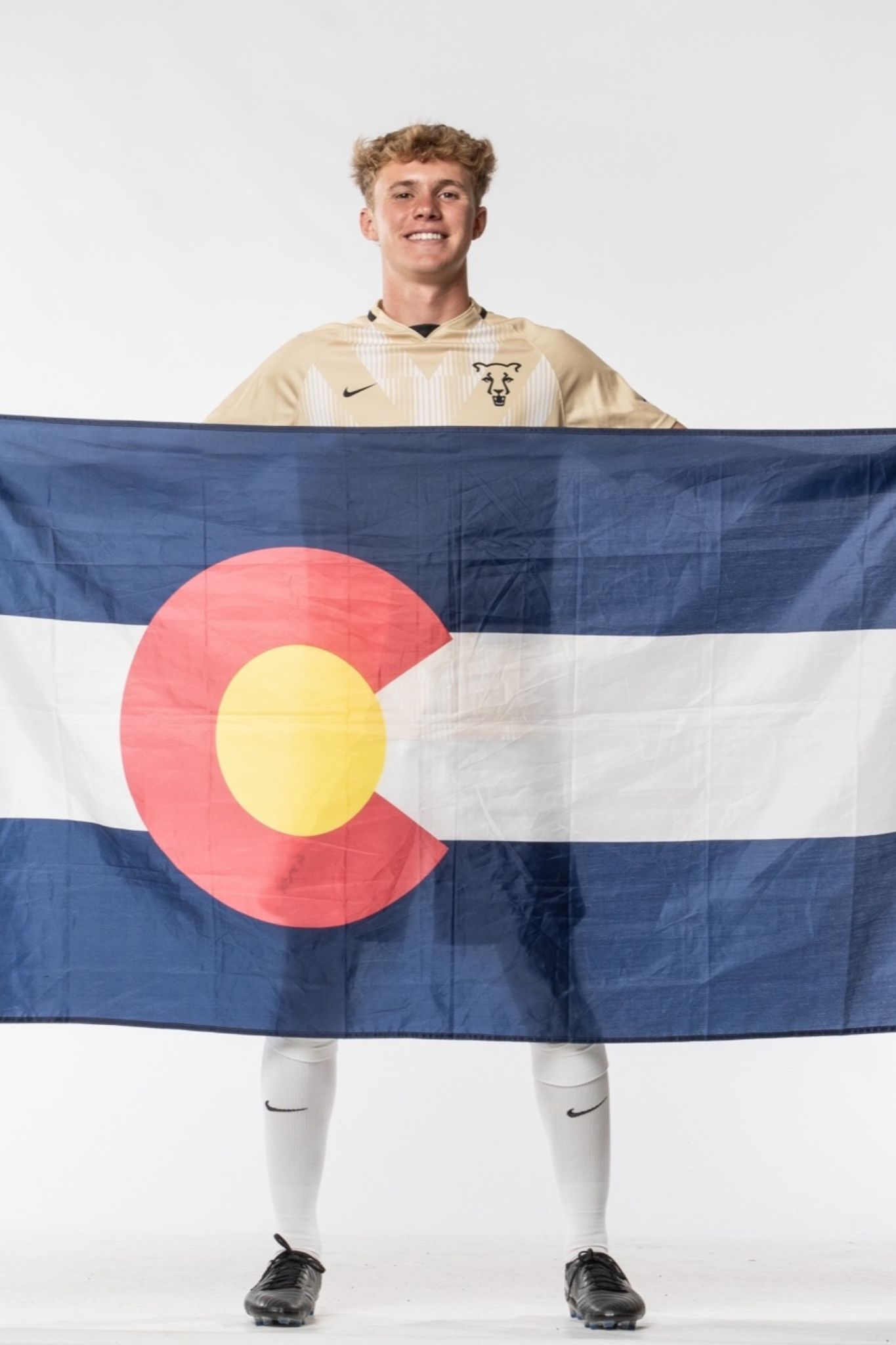 Oliver in his UCCS soccer uniform, holding the Colorado State flag