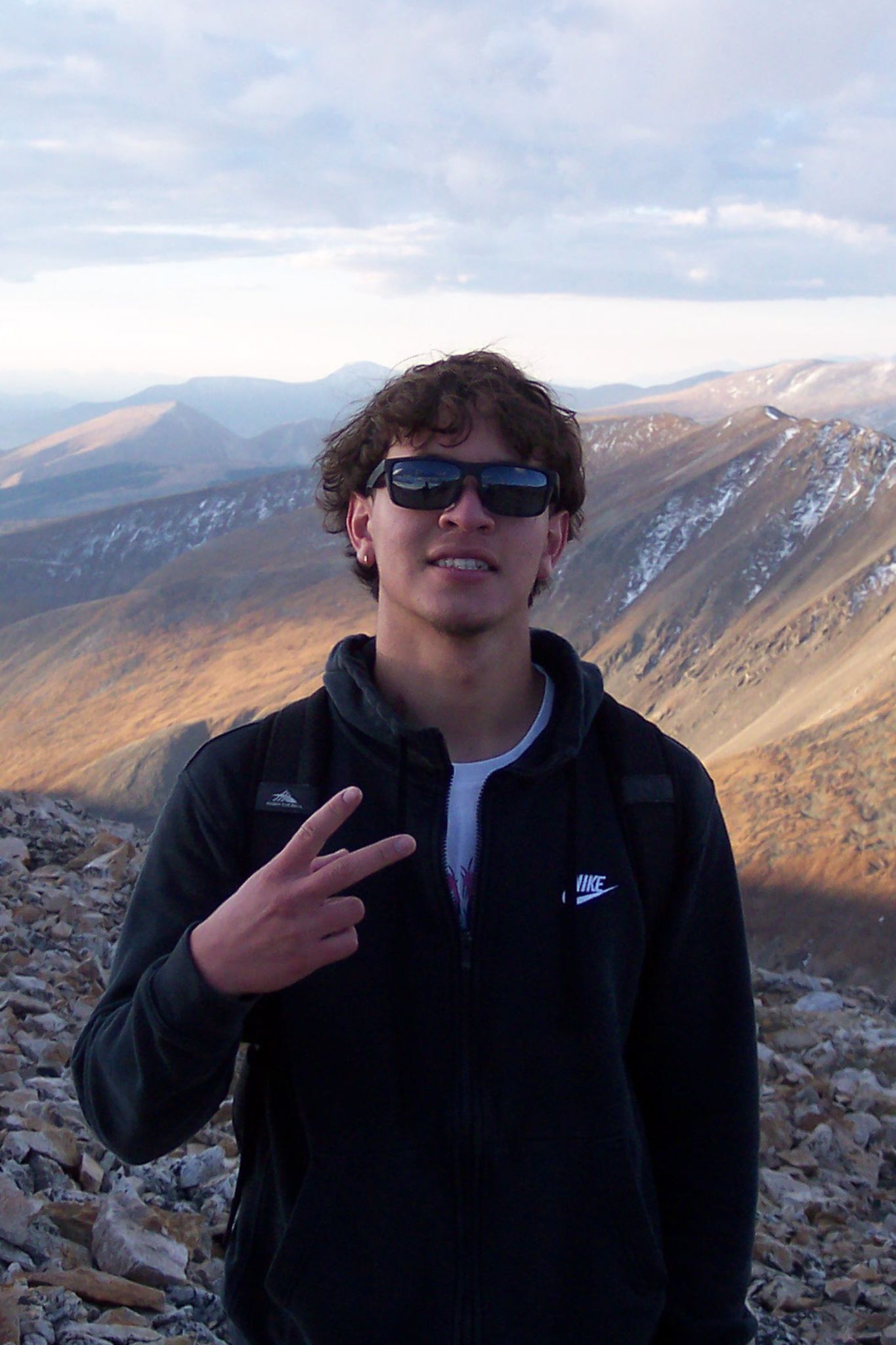 Nelson standing on the mountainside, holding up a peace sign