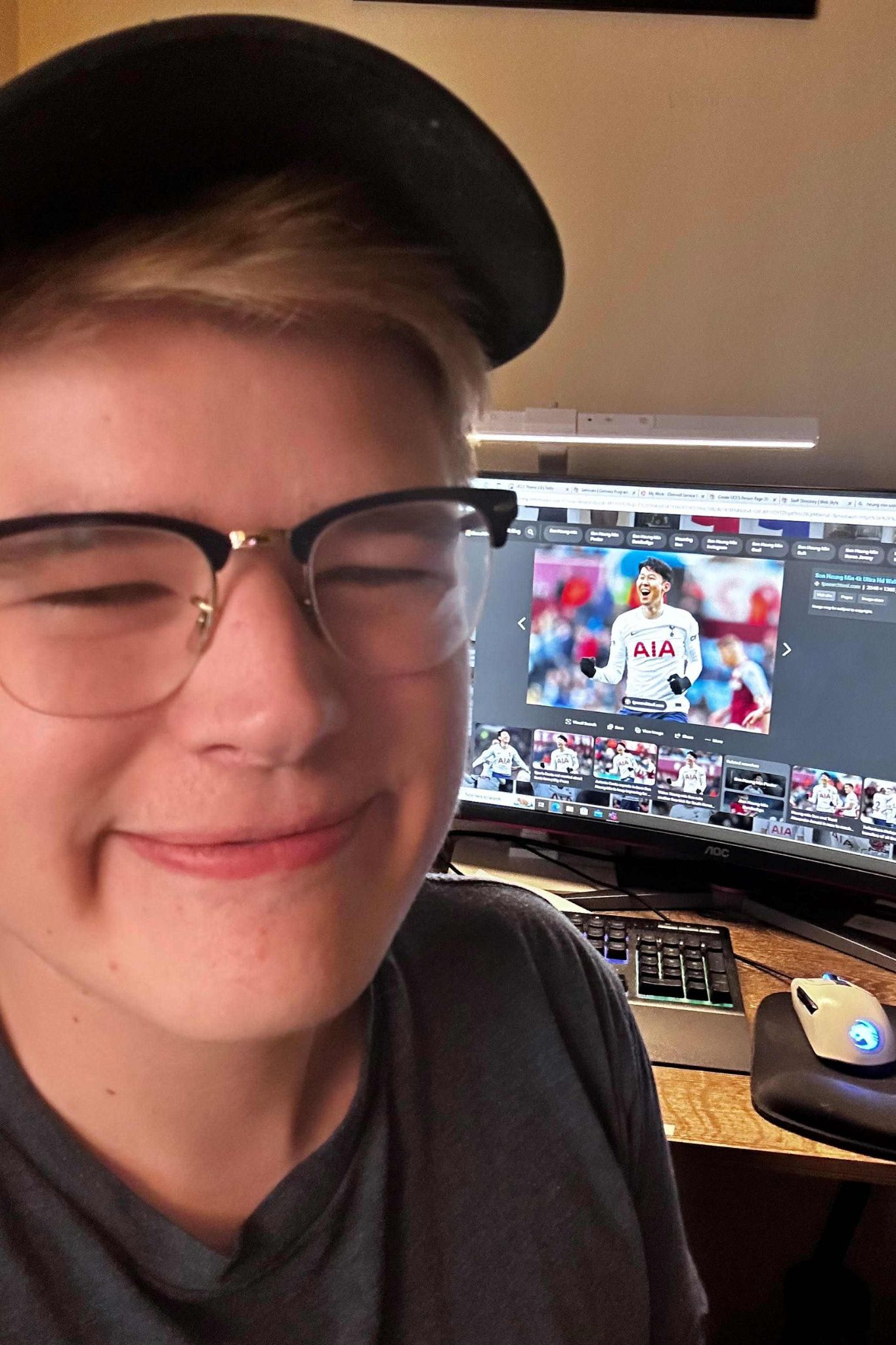 Taylor smiling, standing in front of his computer with a soccer player on the screen